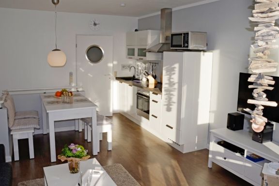 Wohnzimmer mit Küchenzeile, Essplatz, Sofa und Zugang zum Balkon