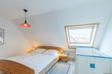 Schlafzimmer mit einem Doppelbett und Kinderbett im Obergeschoss