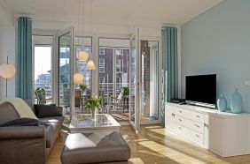 Wohnzimmer mit Sofa und Zugang zur verglasten Loggia und Balkon